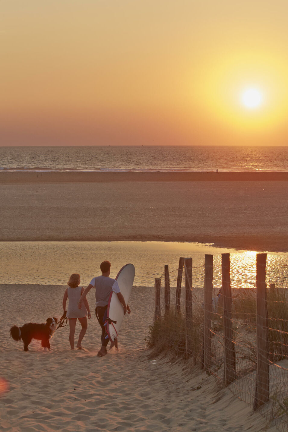 Surfer gehen in der Abenddämmerung an den Strand